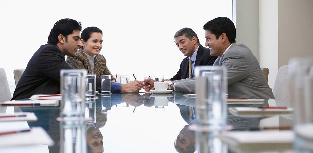 Four Indian business people discussing at conference table